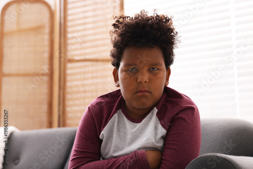 Canvastavla Portrait of resentful little boy sitting on sofa at home