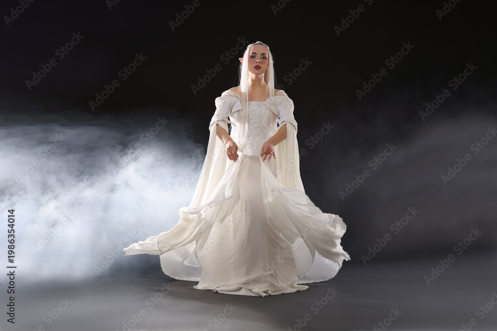 Fototapeta premium Beautiful girl dressed as elf on black background with smoke