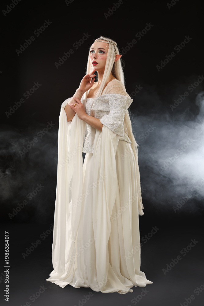 Fototapeta premium Beautiful girl dressed as elf on black background with smoke