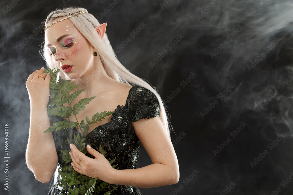 Fototapeta premium Beautiful elf girl with floral decor on black background with smoke, space for text