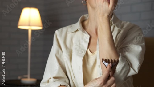 Woman doing gua sha massage on her arm. Relaxed woman performing a therapeutic gua sha self-massage on her arm with a special scraper to improve circulation and stimulate lymphatic drainage