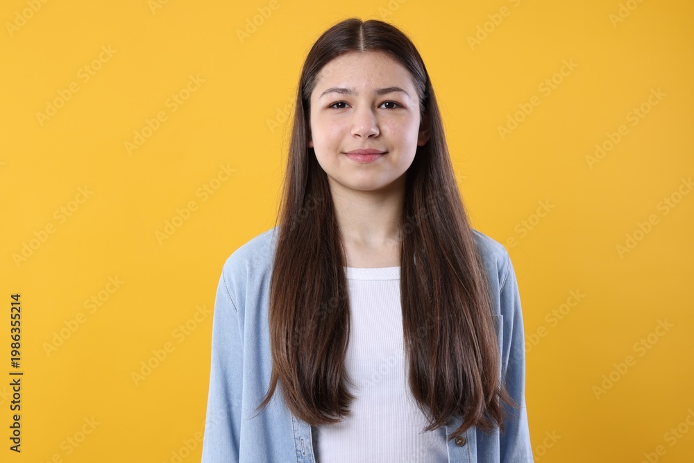 Fototapeta premium Portrait of beautiful teenage girl on orange background