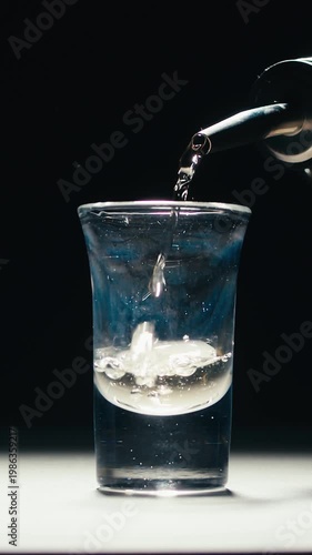 Mexican Tequila Mezcal pouring with lime and salt on a stone table. Strong vodka rum alcoholic drink is poured from a bottle into a shots.