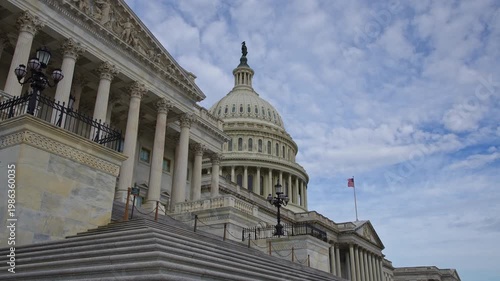American flag waving on US Capitol. American flag in clouds over Capitol dome. American flag symbol of Amerika freedom. American flag on historic Capitol in Washington DC.