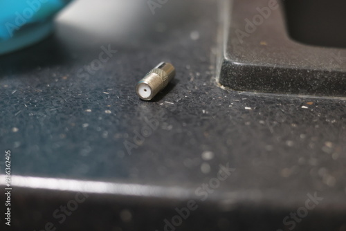 Close-up of a silver coaxial cable connector lying on a textured surface