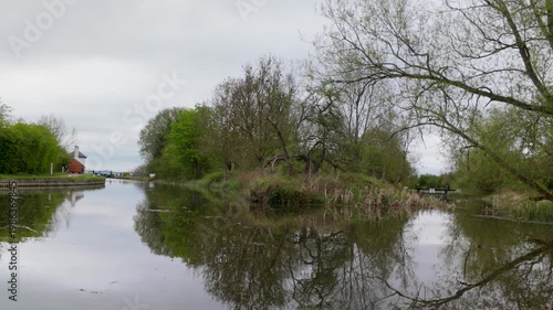Quiet tree-lined canal with reflections on overcast day