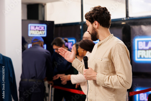 Foto Event host holding microphone announces start of Black Friday sale in modern shopping mall
