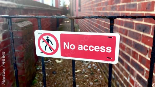 red and white no access sign on iron gate with alley and brick wall background