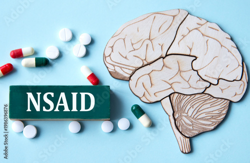 On a blue background with a model of a brain lies a wooden block with the acronym NSAID