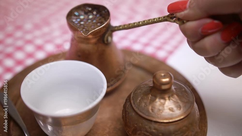 4k video of traditional Turkish coffee served in copper ware being poured into a cup. 
