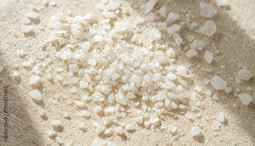 Fine sea salt crystals scattered on natural linen fabric, warm neutral tone, soft side light creating gentle shadows, scattered composition with breathing room