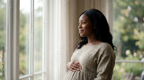 Free Download Pregnant woman by window touching belly expressing peaceful anticipation and maternal connection for lifestyle parenting magazine editorial photography - GFXLoad