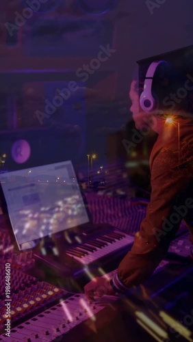 Vertical video: DJ tweaking faders and playing keys after laptop cue to mix under city overlay
