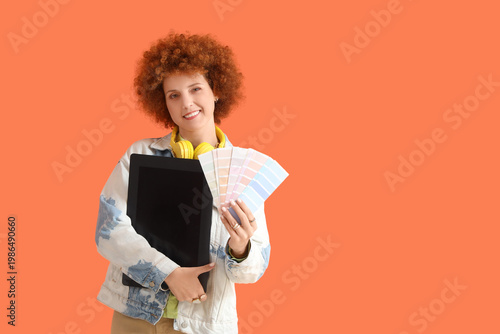 Redhead female graphic designer with tablet and color palettes on orange back...
