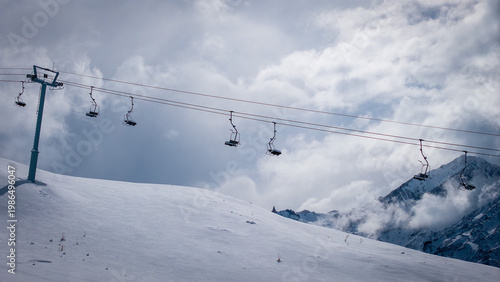Ski lift over snowy mountain slope in Las Lenas Mendoza Argentina under dramatic cloudy sky.
