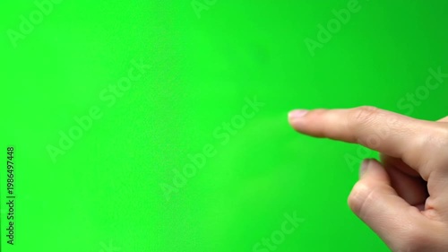 Close-up of a human hand with an index finger pointing on a vibrant green screen background.