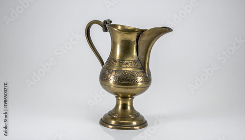 Antique brass pitcher with detailed floral engravings and a sturdy pedestal