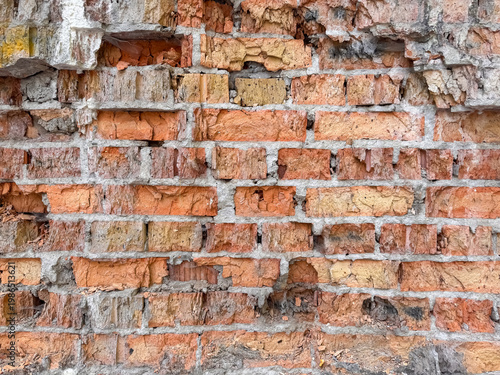 Obraz na plátně Old weathered brick wall with damaged orange yellow and brown bricks showing dec