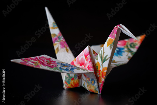 Floral origami crane paper bird colorful pattern black background studio still life hope symbol minimal composition reflective surface tranquil.