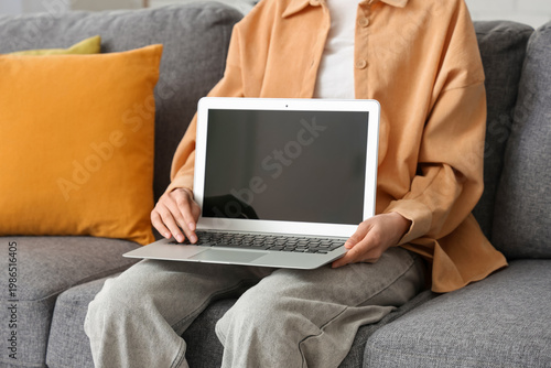 Woman sitting on sofa holdi...