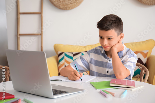 Little boy studying online with laptop at home