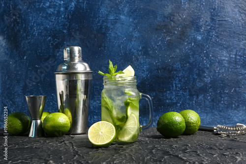 Foto Mason jar of cold mojito and shaker with lime on black table