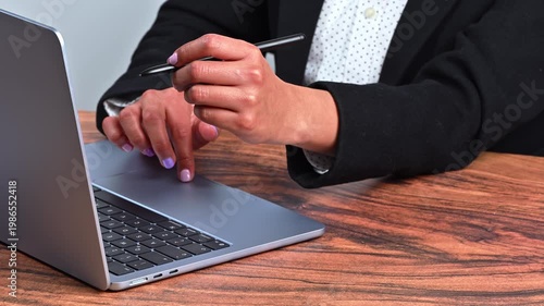 Businesswoman sitting in front of a computer, focus on hands and technology tools