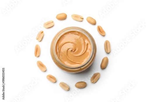 Creamy peanut butter in a glass jar surrounded by fresh peanuts