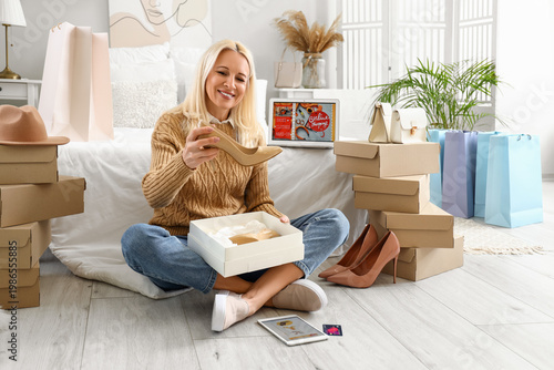 Fotografie Mature woman with new shoes in bedroom. Online shopping