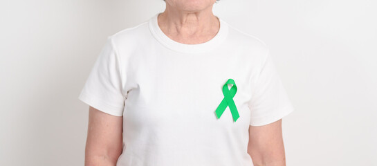 Elderly with Green Ribbon for concept of April Donate Life month, Organ Donation and Transplant Awareness, May Mental Health Awareness month and October Liver cancer. Health and world cancer day