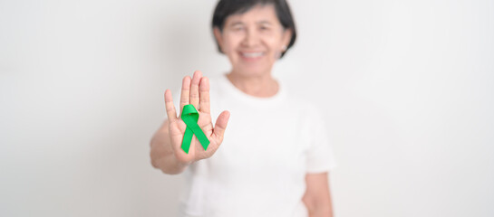 Elderly with Green Ribbon for concept of April Donate Life month, Organ Donation and Transplant Awareness, May Mental Health Awareness month and October Liver cancer. Health and world cancer day