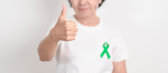 Elderly with Green Ribbon for concept of April Donate Life month, Organ Donation and Transplant Awareness, May Mental Health Awareness month and October Liver cancer. Health and world cancer day