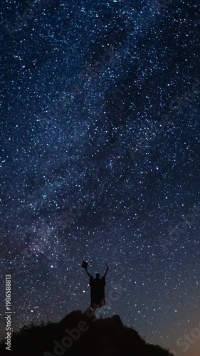 Man on a mountain top watching the amazing milky way night sky. Vertical design in 9:16 ratio. Smartphone and social media ready.