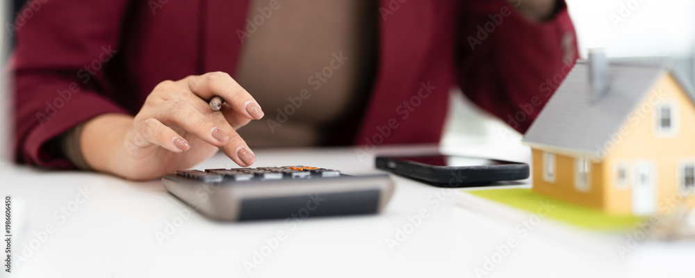 Fototapeta premium Close up of woman accountant using calculator to calculate tax refunds or finance. woman doing finance with calculate expenses with laptop computer on office table.