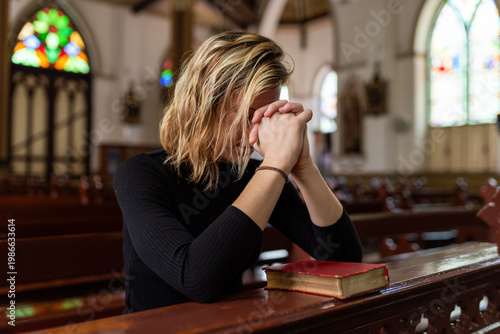 Fotografía Woman praying inside church pew.