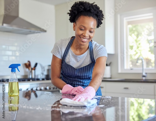 A woman is cleaning the kitchen countertop, showcasing everyday domestic tasks, hygiene, and cleanliness