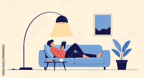 Man relaxes comfortably on a blue sofa while reading an interesting book under the warm light of a floor lamp.