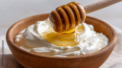 Honey slowly drizzles onto creamy yogurt in bowl.