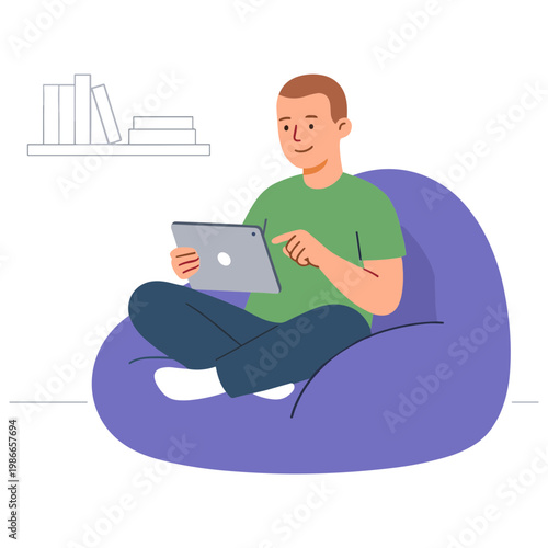 A man sits on a beanbag chair using a tablet indoors
