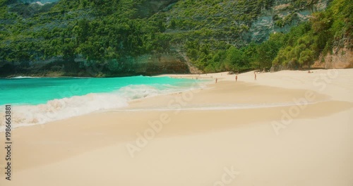 Tourists relaxing on tropical pristine sandy beach Kelingking Bali Nusa Penida
