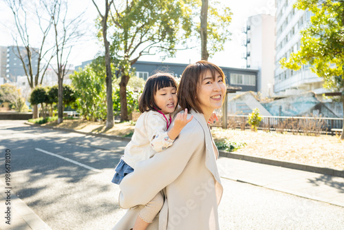Smiling Japanese Mother and Toddler Daughter Looking Up at the Trees in a Sunny Park