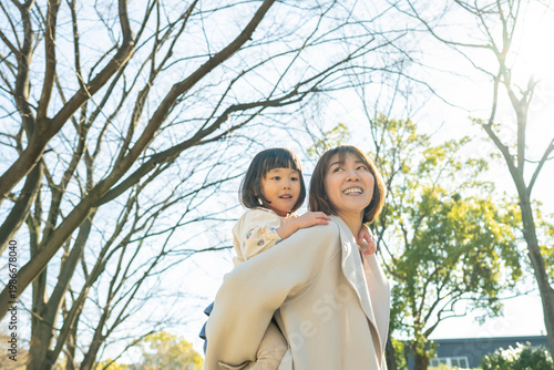 Smiling Japanese Mother and Toddler Daughter Looking Up at the Trees in a Sunny Park