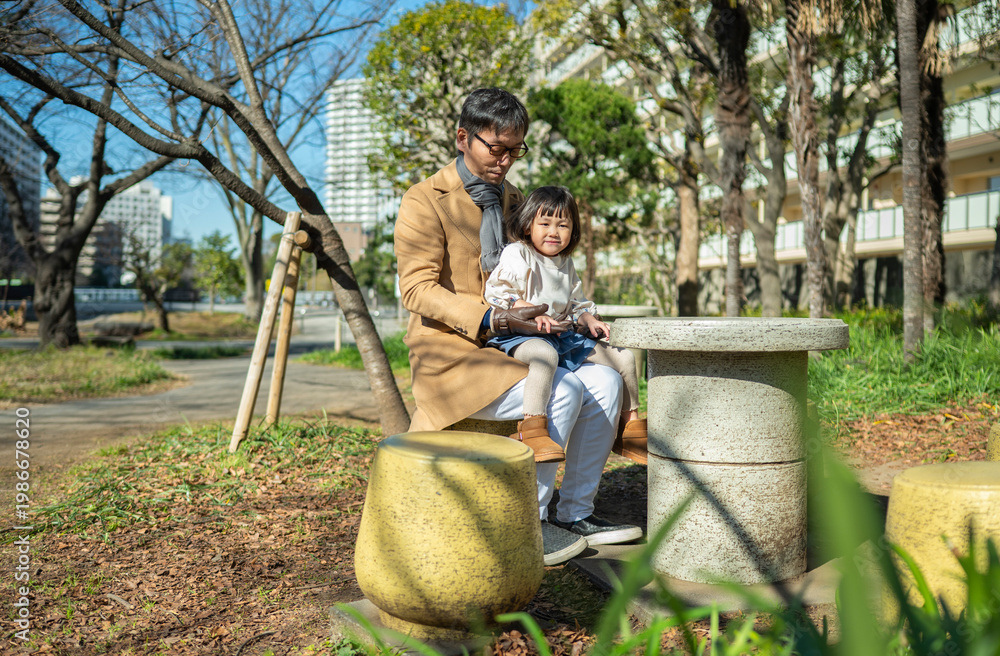 Φωτογραφία Japanese father and little daughter sitting together on a park bench on a sunny