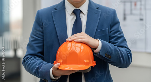Professional engineer in suit holding orange safety hard hat, representing construction industry and planning
