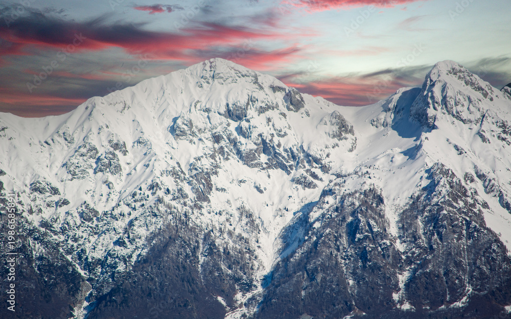 Fototapeta premium a beautiful red sunset over the snow-capped mountains