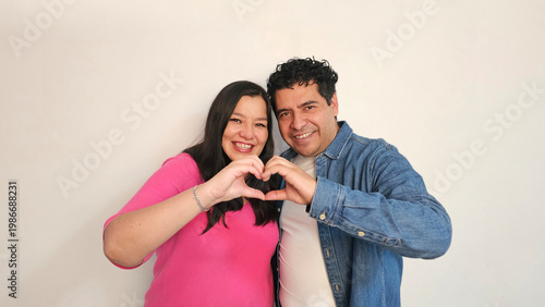 Latino man and woman in their 40s show their love to celebrate Valentine's Day and their anniversary with kisses and hugs, laughing and smiling