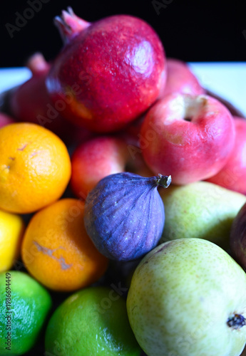 Close-up of ripe fruits including apples, citrus, fig and pomegranate, ideal for healthy lifestyle, organic food and grocery concepts.