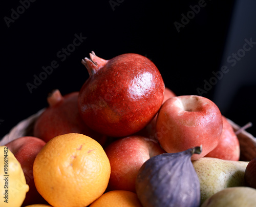Close-up of fresh fruits with pomegranate, apples, citrus and fig on dark background, perfect for healthy food, diet and grocery themes.
