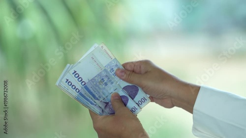 Hands counting and exchanging South Korean Won banknotes, symbolizing cash payment, financial transaction, personal finance, economy, savings, and everyday money exchange.