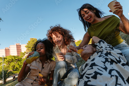 Diverse friends enjoying outdoor picnic with snacks and drinks